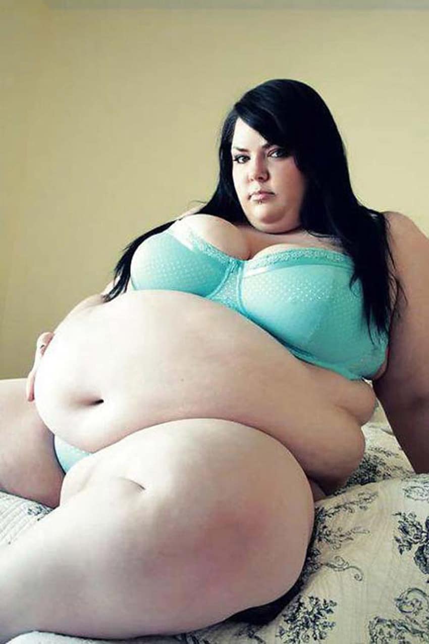 Brune obèse au bidon énorme affalée sur un lit